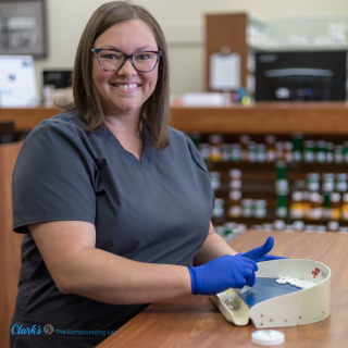 A smiling team member named Rachelle counts out capsules for a patient's custom compounded prescription.
